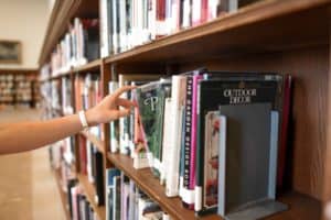 person-holding-book-from-shelf-1370298